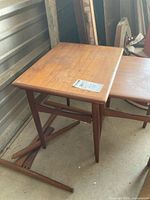 Top view of primary nesting table, second table partially visible, loose wooden parts on floor