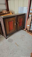 Front view of wooden cabinet showing two red panel doors and handles