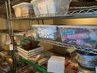 Wide shot showing multiple shelves with plastic bins containing various craft items and supplies including cups, flowers, paint brushes, and packaging.