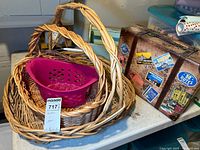 Three wicker baskets, purple plastic basket, vintage suitcase style box with travel stickers, and a wooden box arranged on a table
