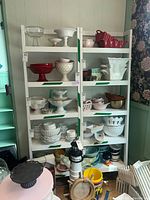 Two white wooden bookshelves filled with various household items shown from front, highlighting shelves and size.