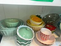 Wide view of all ceramic bowls and dish with lid showing variety of colors and sizes