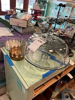 Glass cake plate with dome cloche on light-colored cabinet.