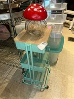 Metal cart with wood top and glass mushroom jar on top.