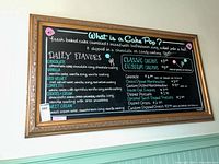 Framed chalk board with colorful chalk writing describing cake pop flavors and prices, taken from a front angle.