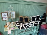 Photo of multiple chalk board signs with vintage style white distressed frames, table top easel, and metal wire basket on decorative metal display stand.