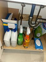 Photo of various cleaning products under a sink, including Lysol Toilet Bowl Cleaner, trigger spray cleaners, a box of Clorox tablets, and Clorox disinfecting wipes.