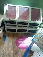 Top side view of two white display cabinets with glass front panels and four drawers each, showing wear and aging.