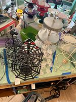 Wide view of multiple multi-tier display plates arranged on a table showing metal spider web themed stand, white snowflake design stand, and colorful ceramic plates.