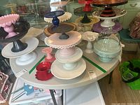 Square white folding table with black metal frame and legs seen supporting cake stands and other items (not included).