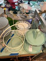 Photo showing four metal display stands in various styles and colors on a glass table.