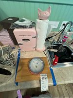 Pink Frigidaire mini fridge, paper towel holder, wooden cutting board, ceramic bowls, and kitchen sink area.