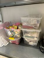 Three plastic storage bins stacked, two are clear with lids, one is open showing baking items and molds