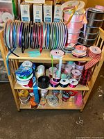 Wide shelf with multiple ribbon spools arranged by size and color, showing variety of ribbons.