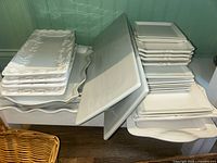 Stack of white ceramic rectangular serving trays with scalloped edges and embossed decorative patterns