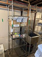 Full view of the wire shelving unit with boxes and small containers on the shelves, showing metal wire grid shelves and caster wheels.