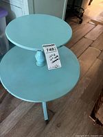 Photo of blue two-tier round accent table showing top and base tiers with single central support and three legs.