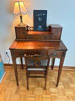 Front view of the writing desk with cubbies, central drawer and lamp on top