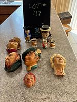 Image showing four Bosson's wall masks and a collection of miniature character mugs and vase on countertop.