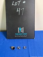Photo showing all three costume jewelry rings on a blue fabric background with a black box behind marked Lot # 47.