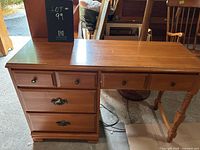 Full front view of wooden desk showcasing drawers and turned legs.