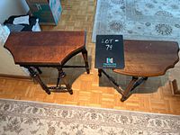 Photo showing two vintage half moon wooden tables with tapered edges and turned legs, placed on a wood floor with part of a rug visible.