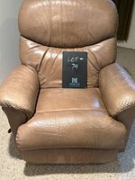Front view of the creamy taupe leather oversized recliner rocking chair with natural light showing leather texture and padding.