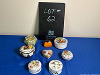 Full set of miniature jewelry boxes arranged on blue cloth background with lot identification in background.