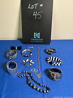 Several bracelets and a necklace arranged on blue background with lot number card in view, showing assortment of costume jewelry items by shape, size, and material.