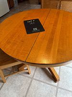 Close-up top view of round light oak table showing wood grain and pedestal base legs.