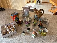Assortment of animal and bird figurines, including birds and novelty pieces on table.