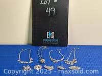 Photo showing five necklaces and five brooches arranged on blue background with a black display board behind, indicating lot number.