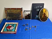 Full lot of four stained glass panels and pewter keepsakes with items arranged on a blue tablecloth