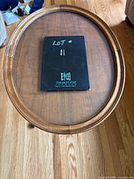 Top view of the oval wooden side table showing the removable glass top and wooden rim.