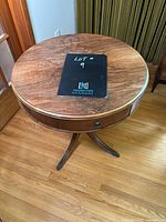 Top side view of round wooden table showing wood grain and drawer front details.