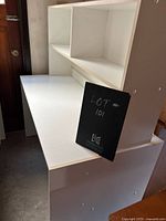 Smaller white desk with three drawers and an unattached credenza visible behind it, showing the structure and finish.