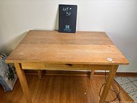 Front view of the vintage wooden writing desk showing rectangular top and single centered drawer with wooden handle.