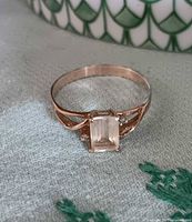 Ring top view showing rectangular pale yellow center stone and clear accents in gold setting