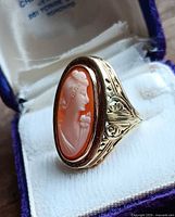 Front angled view of the cameo ring in box showing carving and gold shoulder detail