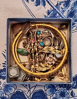 Top view of box showing assorted broken costume jewelry