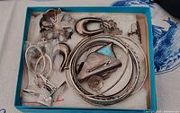 Overview of jewelry in box showing pendants, bangles, brooch, loose earrings