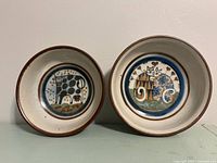Both stoneware bowls side by side showing size difference and interior illustrations