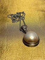 Front view of sterling silver necklace showcasing domed Mabe pearl pendant and decorative bail