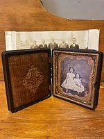 Open thermoplastic union case showing interior velvet pad and framed carte-de-visite; group photo visible behind