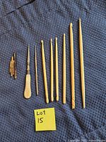 All crochet hooks, needles and awl laid out on blue fabric