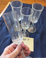 Four crystal champagne flutes displayed on cloth; one held to show cut crystal detail