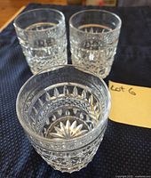 Three cut crystal tumblers on dark cloth with lot tag visible