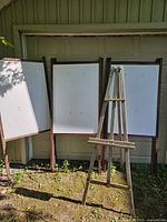 Three of the wooden display panels standing upright beside the wooden easel