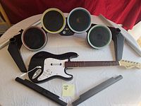 Entire lot showing drum kit with four coloured pads, stand legs, and black Stratocaster-style guitar controller