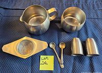 All seven pieces laid out: creamer, sugar bowl, tea strainer, pair of spoons, salt and pepper shakers